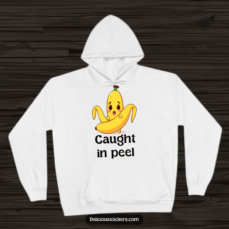 Funny hoodie featuring a surprised banana character peeking out from a large banana peel, offering comfort and humor.